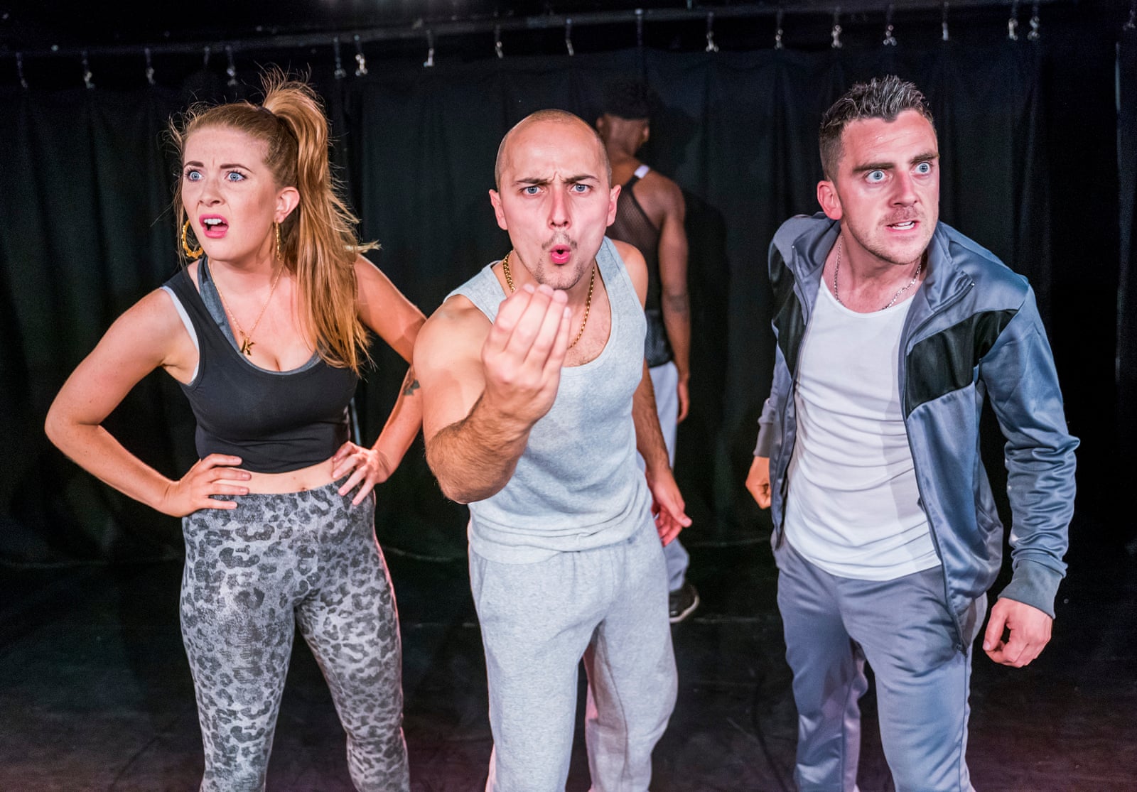 Three performers in tracksuits facing the audience in Flesh and Bone