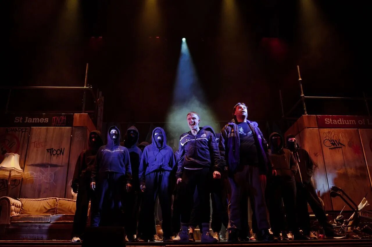 The Gerry & Sewell company lit by a single spotlight in front of the terrace set