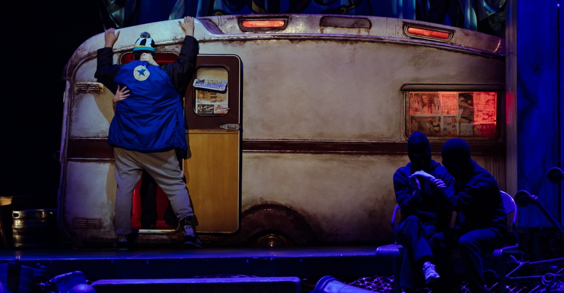 A caravan scene from Gerry & Sewell lit in deep blue and red stage light